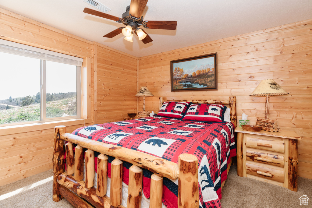 Bedroom with carpet flooring, wood walls, and a ceiling fan
