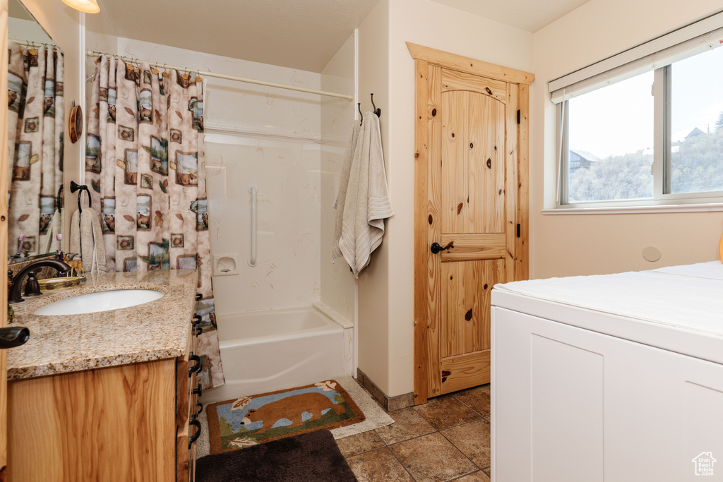 Full bath with vanity, shower / bathtub combination with curtain, washer / dryer, baseboards, and stone finish floors