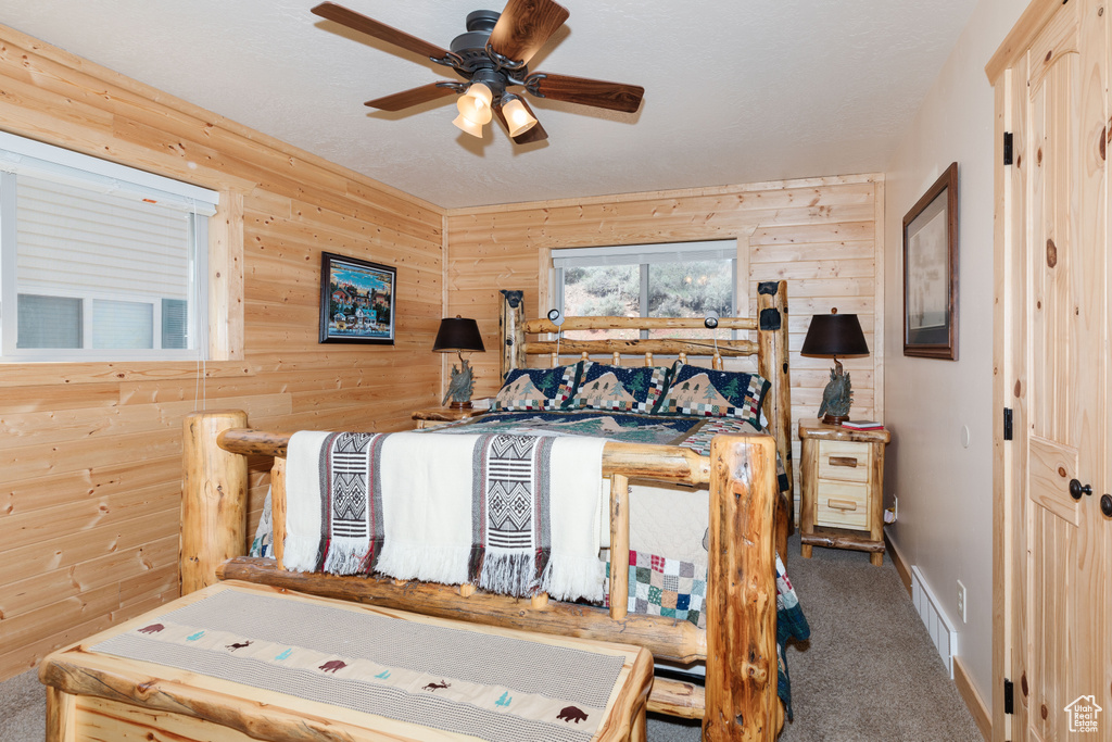 Bedroom featuring wooden walls, carpet floors, baseboards, and a ceiling fan