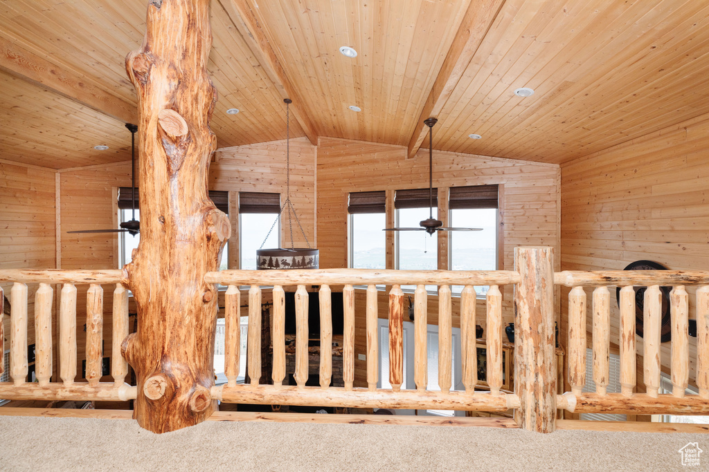 Hallway with wooden walls, carpet flooring, and wood ceiling