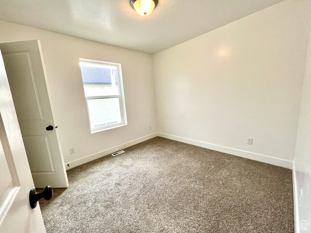 Unfurnished room with dark carpet and baseboards