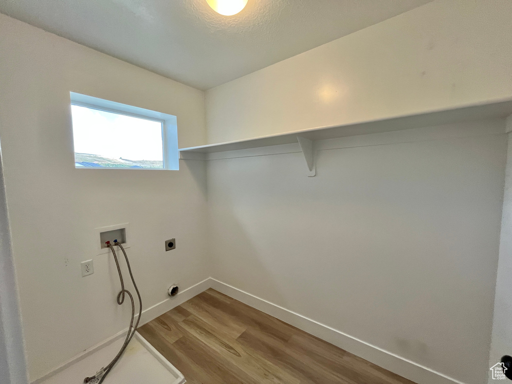 Laundry room with hookup for a washing machine, light wood finished floors, electric dryer hookup, and baseboards