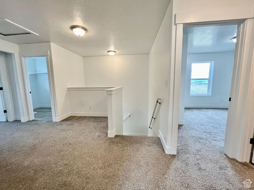 Carpeted spare room featuring a textured ceiling and baseboards