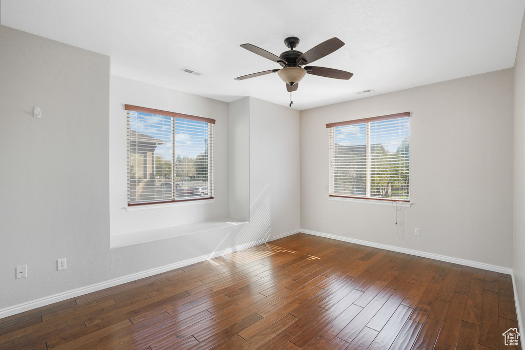 Empty room with baseboards, wood-type flooring, healthy amount of natural light, and a ceiling fan