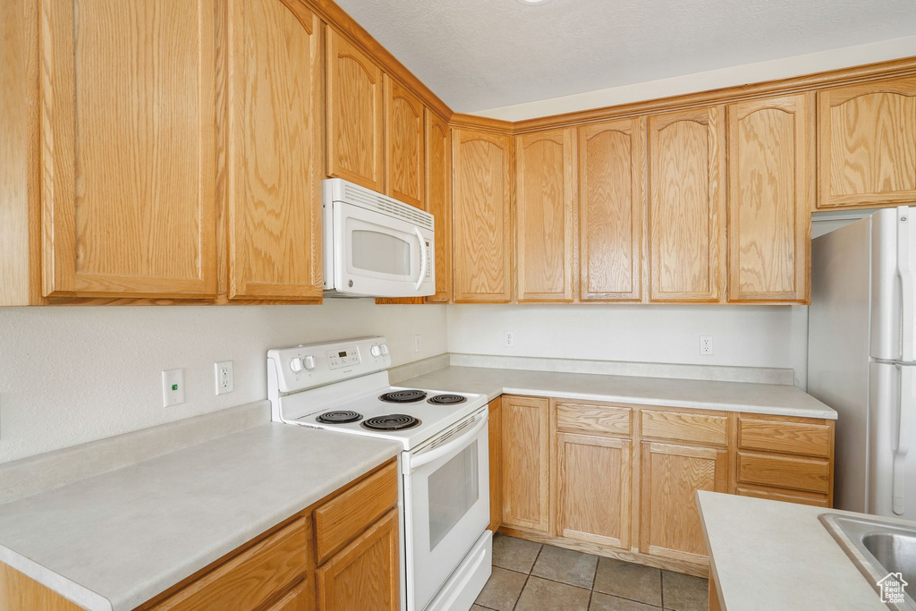 Kitchen featuring white appliances, light countertops, and light tile patterned flooring