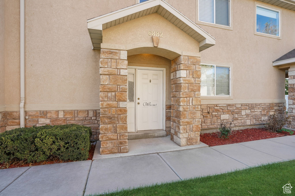 Entrance to property with stone siding and stucco siding