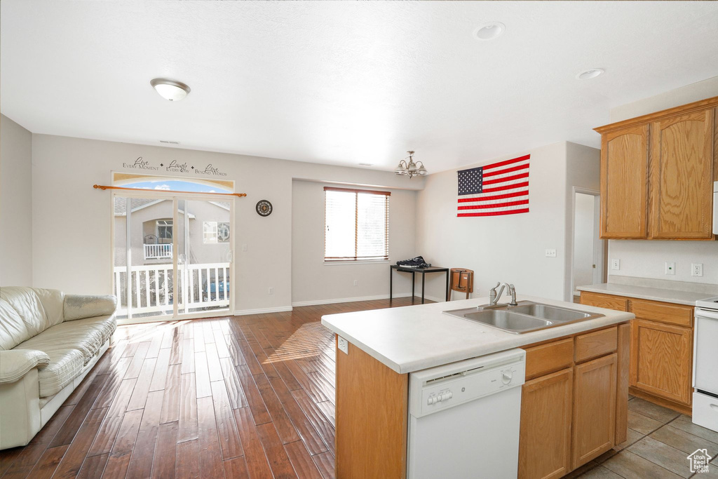 Kitchen featuring white appliances, open floor plan, a sink, light countertops, and a kitchen island with sink