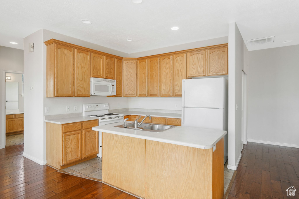 Kitchen with white appliances, a sink, dark wood finished floors, light countertops, and a kitchen island with sink