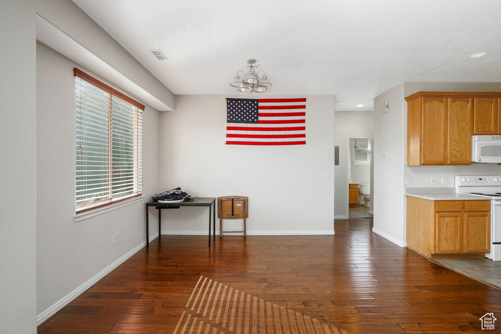 Unfurnished dining area featuring a chandelier, dark wood finished floors, baseboards, and recessed lighting