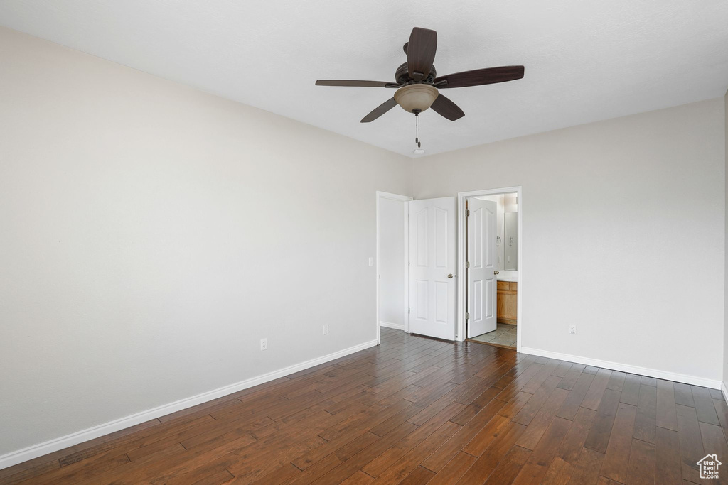 Spare room featuring baseboards, dark wood-style floors, and ceiling fan