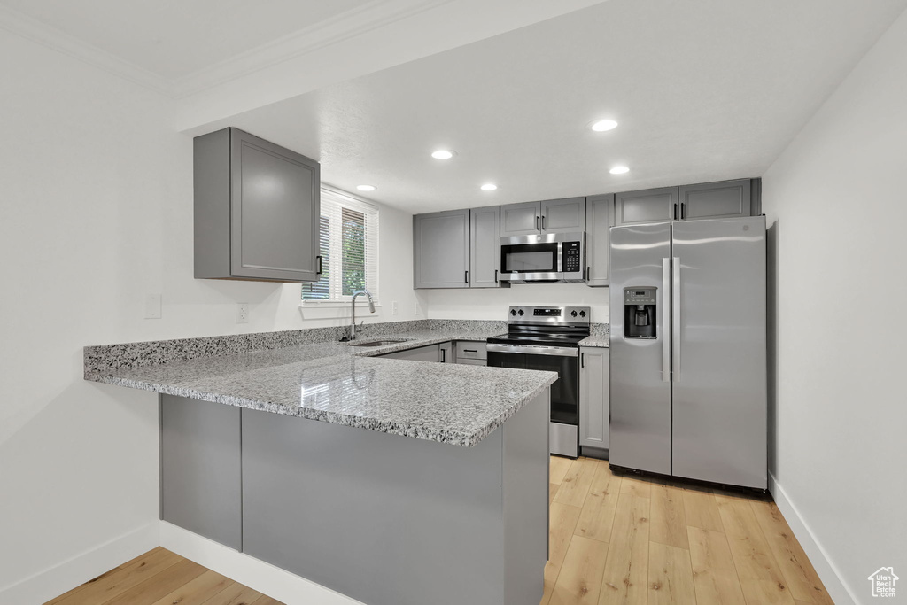 Kitchen with appliances with stainless steel finishes, gray cabinets, a peninsula, a sink, and recessed lighting