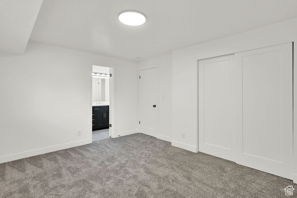 Unfurnished bedroom with carpet flooring, baseboards, and ensuite bath