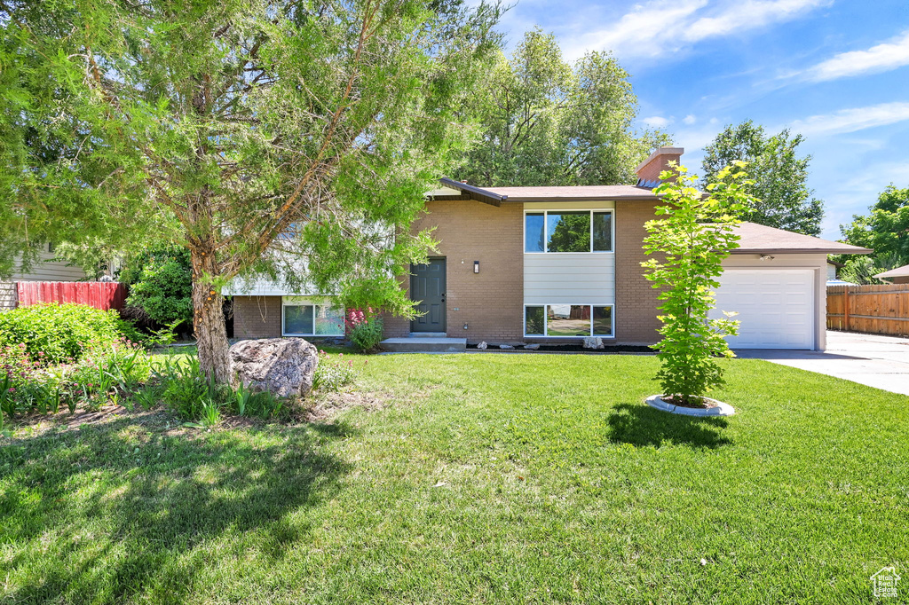 View of front of house featuring brick siding, concrete driveway, a garage, and a chimney