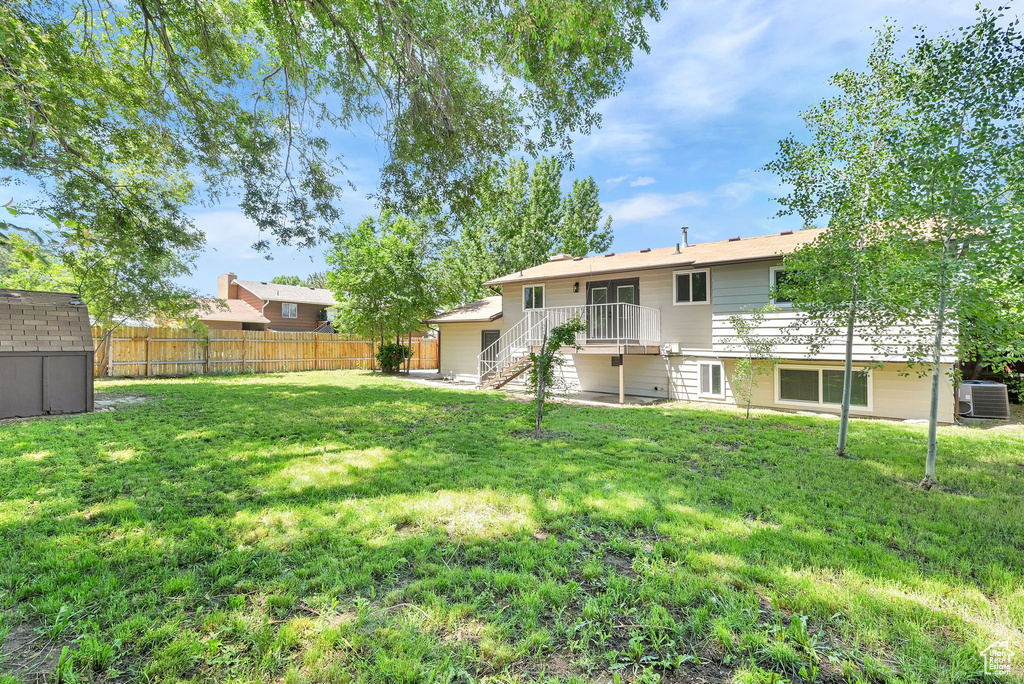 Rear view of property featuring central AC and stairway