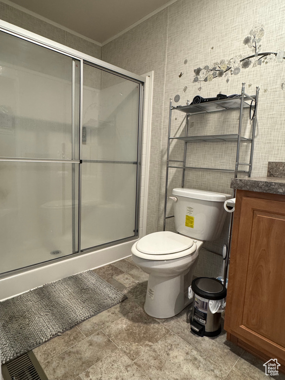 Bathroom with ornamental molding, toilet, a shower stall, vanity, and stone finish flooring