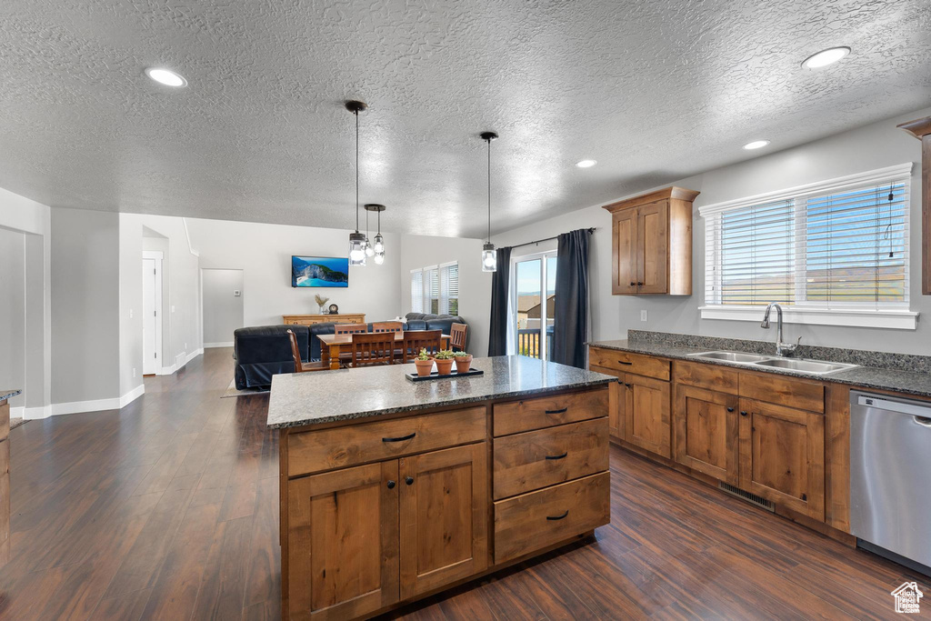 Kitchen featuring a sink, stainless steel dishwasher, a textured ceiling, dark wood-style flooring, and a center island