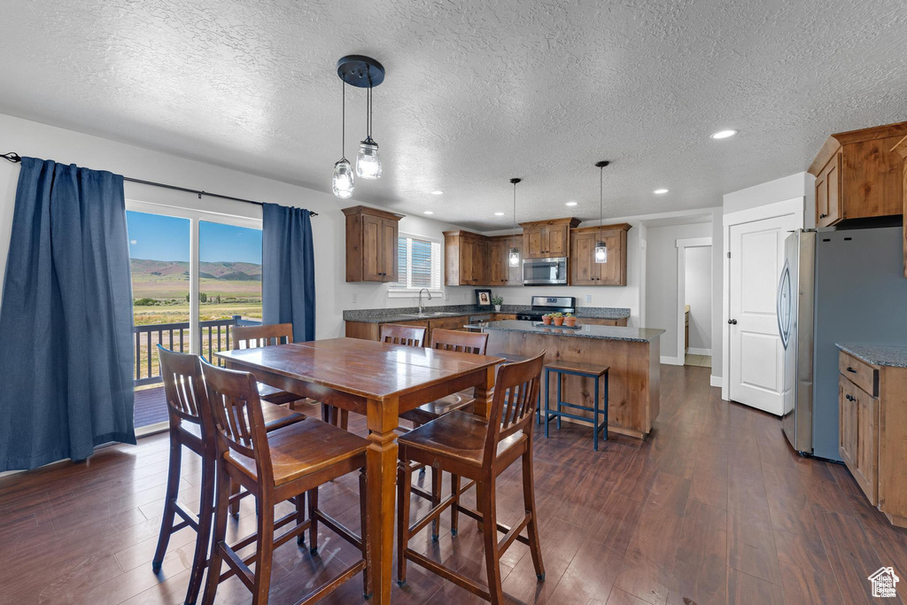 Dining space featuring a textured ceiling, recessed lighting, and dark wood-type flooring