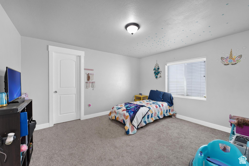 Bedroom with carpet, baseboards, and a textured ceiling