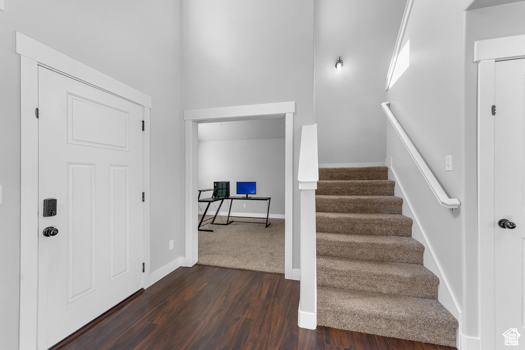 Foyer entrance featuring dark wood-type flooring, stairway, and baseboards