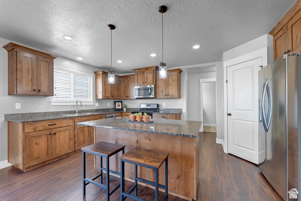Kitchen featuring appliances with stainless steel finishes, a sink, dark wood-type flooring, a textured ceiling, and recessed lighting