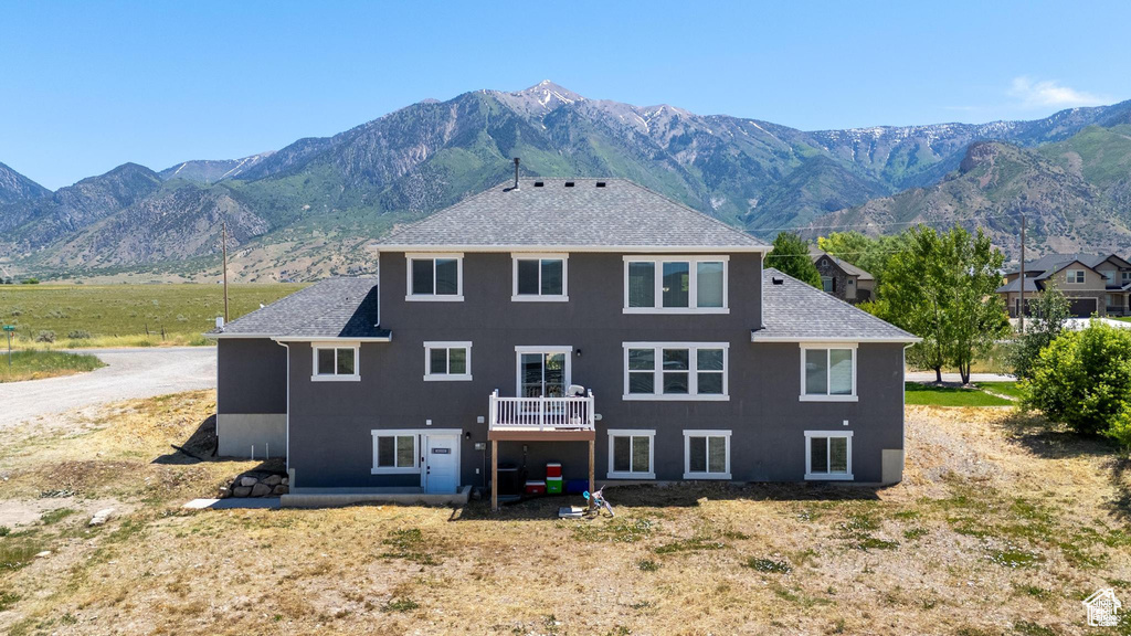Back of property with a shingled roof and a mountain view