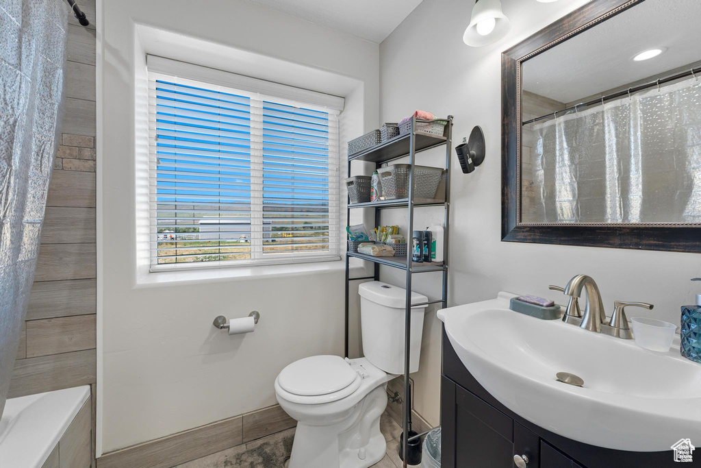 Bathroom featuring vanity, toilet, a shower with curtain, and a tub