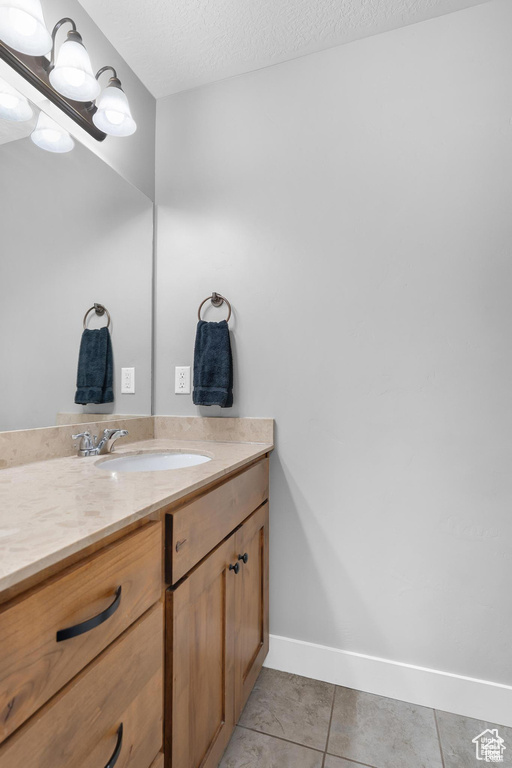 Bathroom featuring vanity, tile patterned floors, baseboards, and a textured ceiling