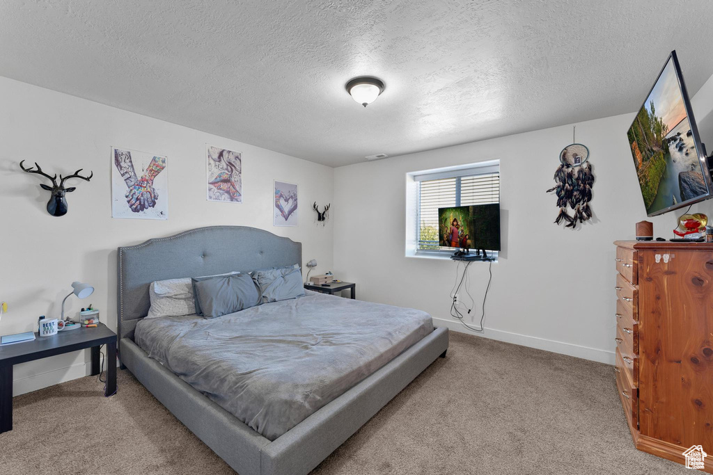 Carpeted bedroom featuring a textured ceiling and baseboards