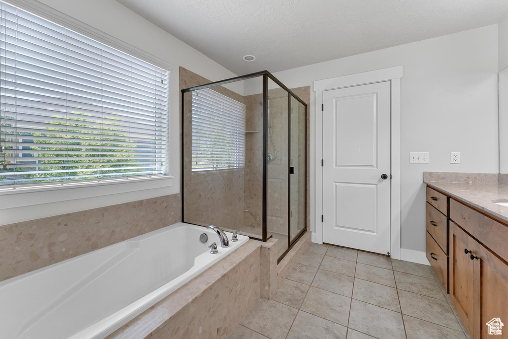 Full bath featuring a bath, a shower stall, vanity, and tile patterned flooring