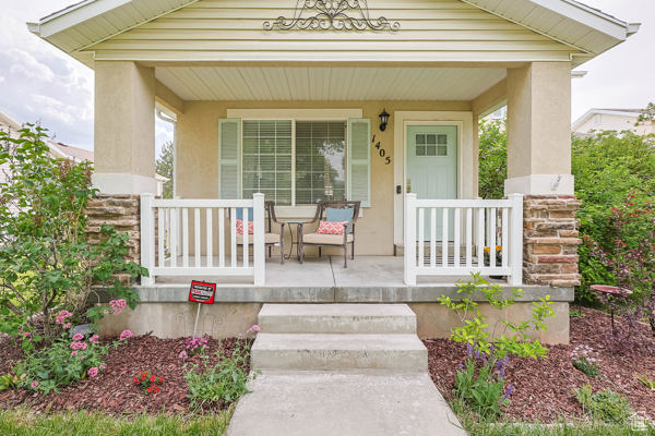 View of exterior entry with covered porch and stucco siding