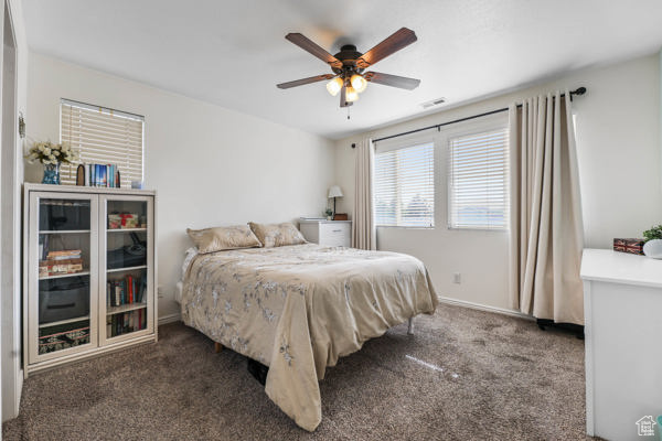 Carpeted bedroom featuring ceiling fan