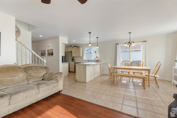 Living area featuring a ceiling fan, a chandelier, stairway, light tile patterned floors, and baseboards