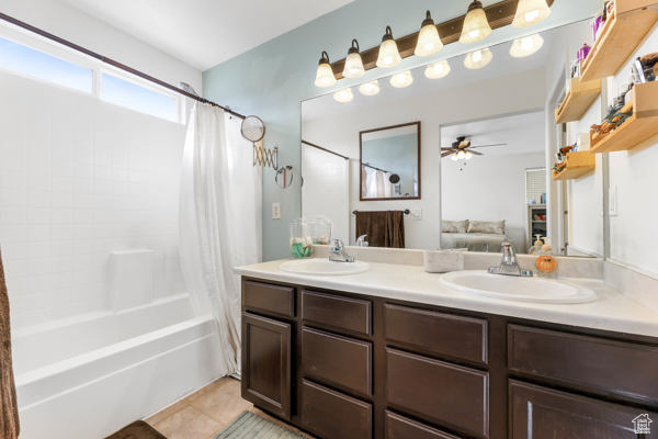 Full bath featuring double vanity, ceiling fan, tile patterned flooring, shower / bathtub combination with curtain, and ensuite bathroom