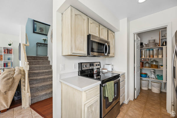 Kitchen with appliances with stainless steel finishes, light brown cabinets, light countertops, and light tile patterned flooring