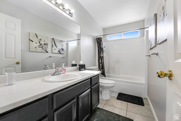 Full bathroom featuring toilet, vanity, shower / bath combo, and tile patterned flooring