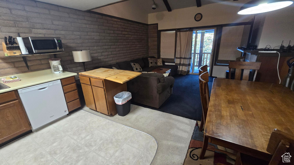 Kitchen featuring dishwasher, stainless steel microwave, brown cabinetry, brick wall, and butcher block counters