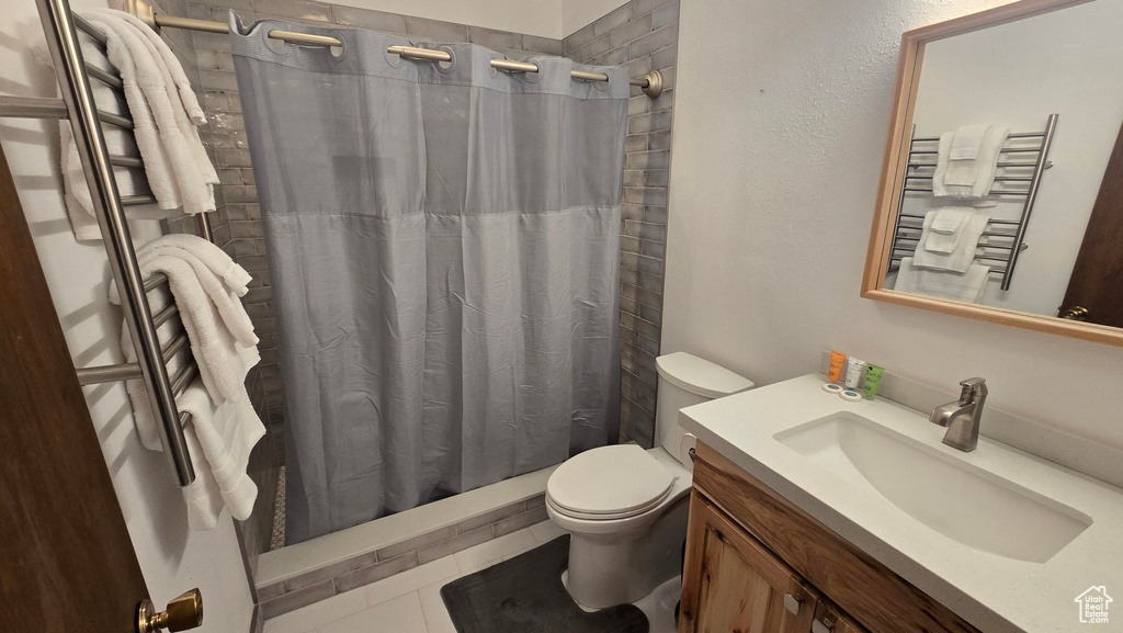 Bathroom featuring radiator, vanity, toilet, a towel warming rack, and curtained shower