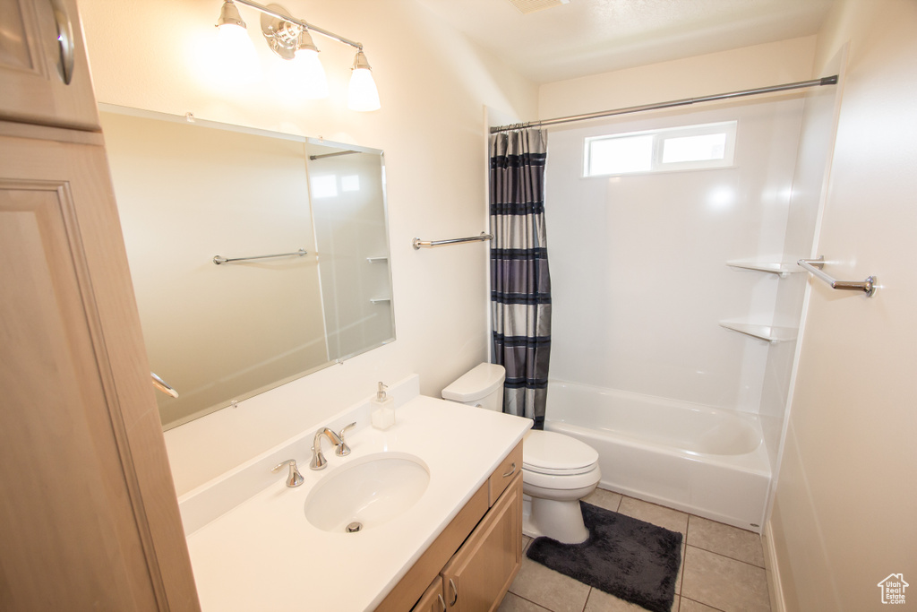 Bathroom featuring vanity, toilet, tile patterned flooring, and shower / bath combination with curtain