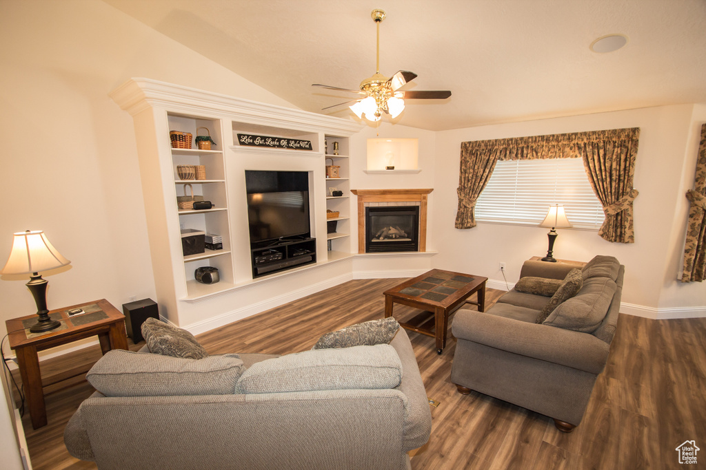 Living room with ceiling fan, wood finished floors, vaulted ceiling, and a glass covered fireplace
