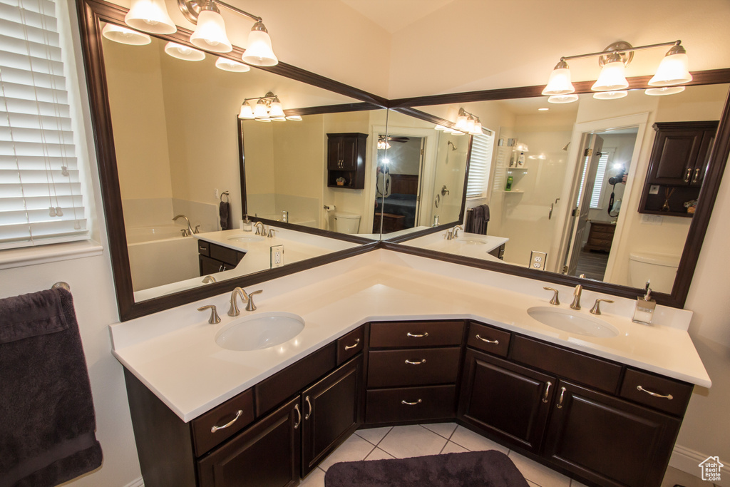 Bathroom featuring toilet, double vanity, tile patterned floors, and a shower stall