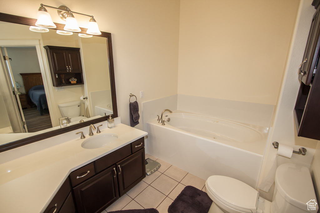Bathroom featuring toilet, a bath, tile patterned flooring, ensuite bathroom, and vanity