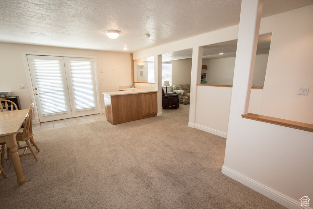 Kitchen with light carpet, a textured ceiling, brown cabinetry, healthy amount of natural light, and light countertops