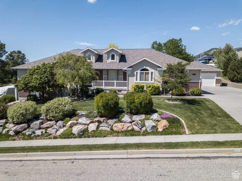 View of front facade featuring concrete driveway, a front lawn, an attached garage, and a shingled roof