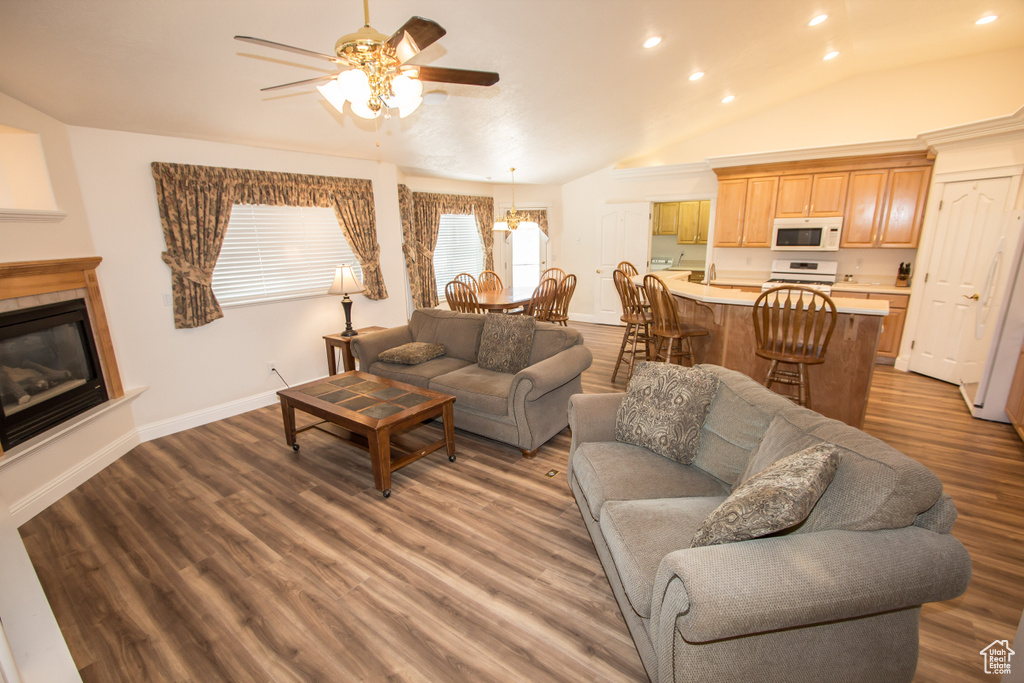Living room with a ceiling fan, recessed lighting, wood finished floors, a glass covered fireplace, and lofted ceiling