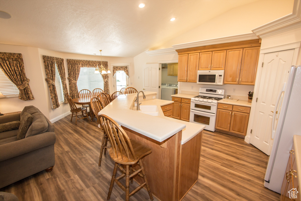 Kitchen with white appliances, a sink, lofted ceiling, a chandelier, and a kitchen breakfast bar