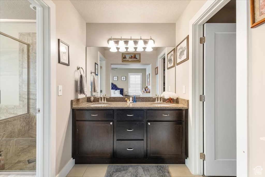 Full bath featuring a stall shower, double vanity, baseboards, and tile patterned floors
