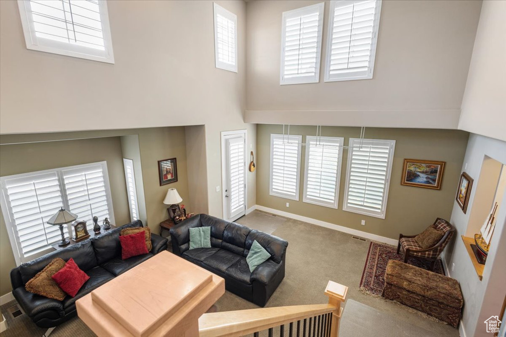 Carpeted living room featuring a high ceiling and baseboards