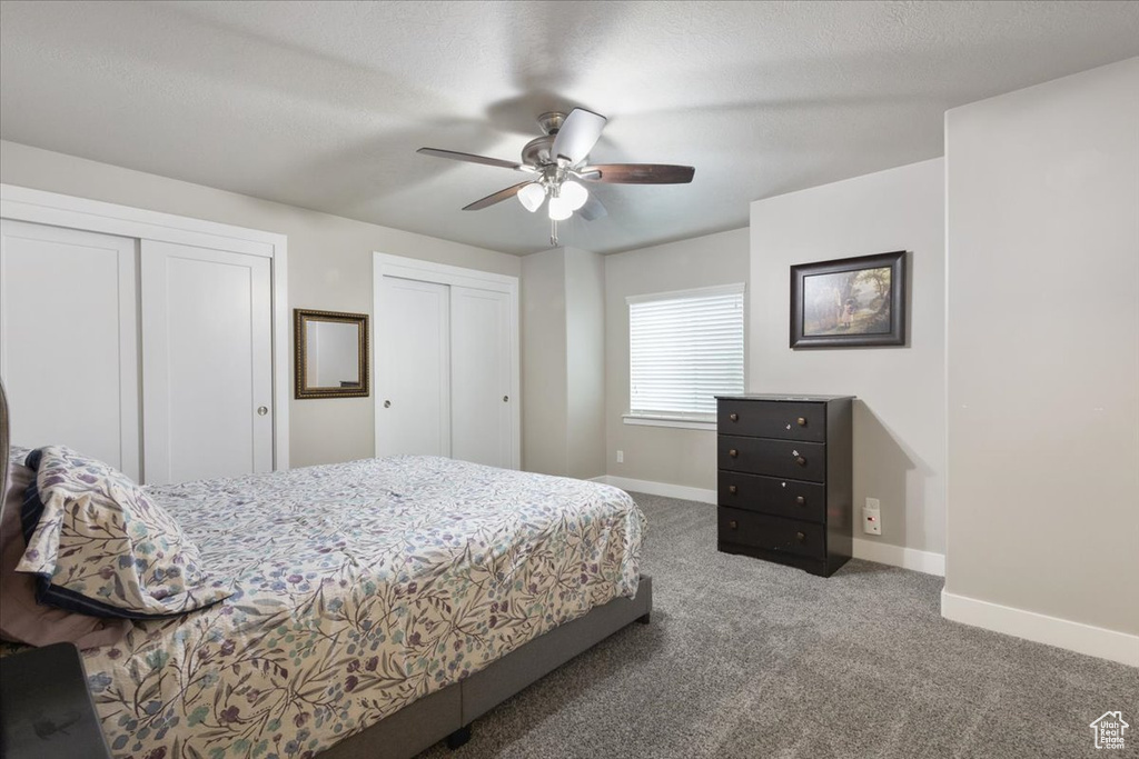 Bedroom featuring baseboards, carpet floors, multiple closets, and a ceiling fan