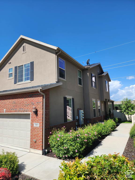 View of property exterior featuring stucco siding, a garage, and brick siding