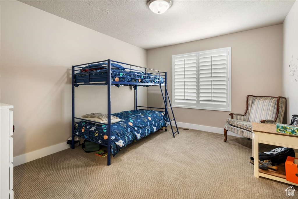 Carpeted bedroom featuring baseboards and a textured ceiling